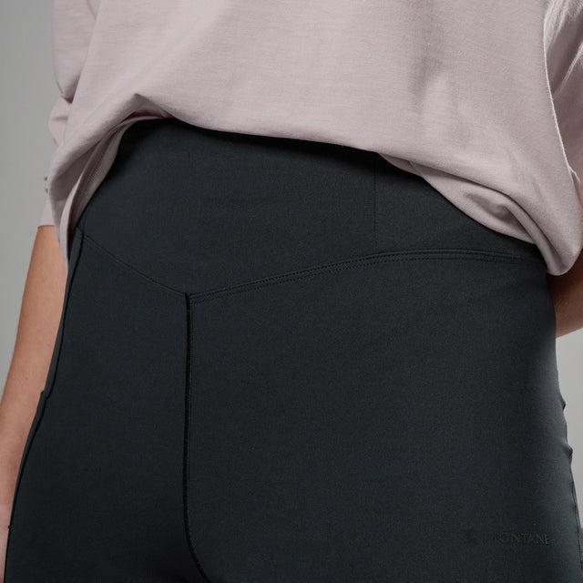 Person wearing black leggings and a light grey shirt on a plain background