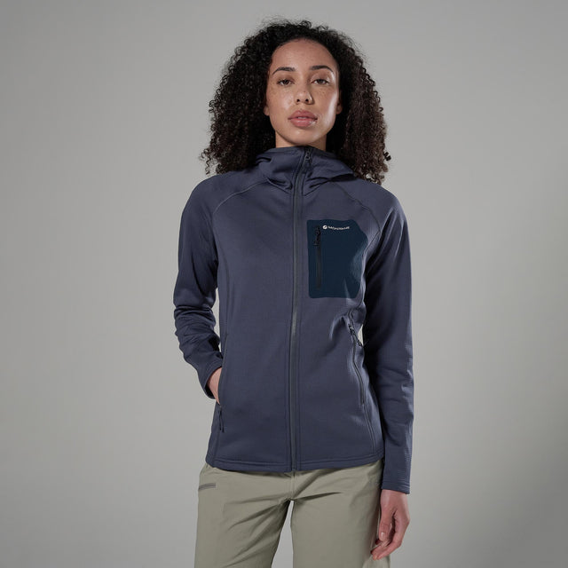 Woman wearing a dark blue jacket with a Montane logo on a grey background