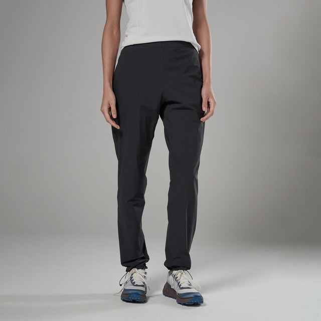 Person wearing black pants and white sneakers on a gray background