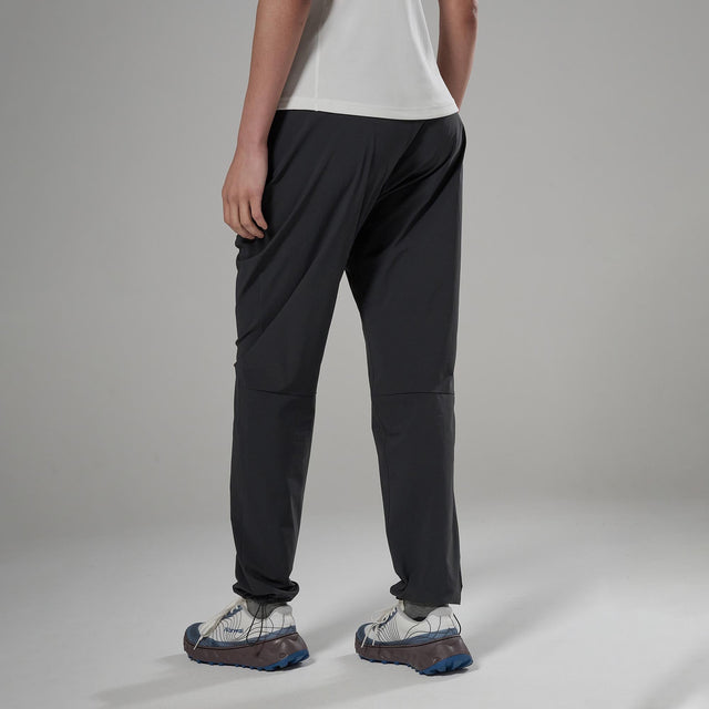 Person wearing black pants and white shoes on a grey background