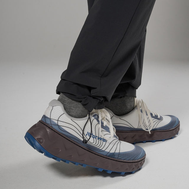 White sneakers with blue accents worn with black pants on a neutral background