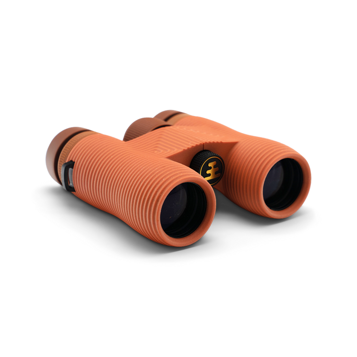 Compact orange binoculars with Nocs Provisions logo on a white background