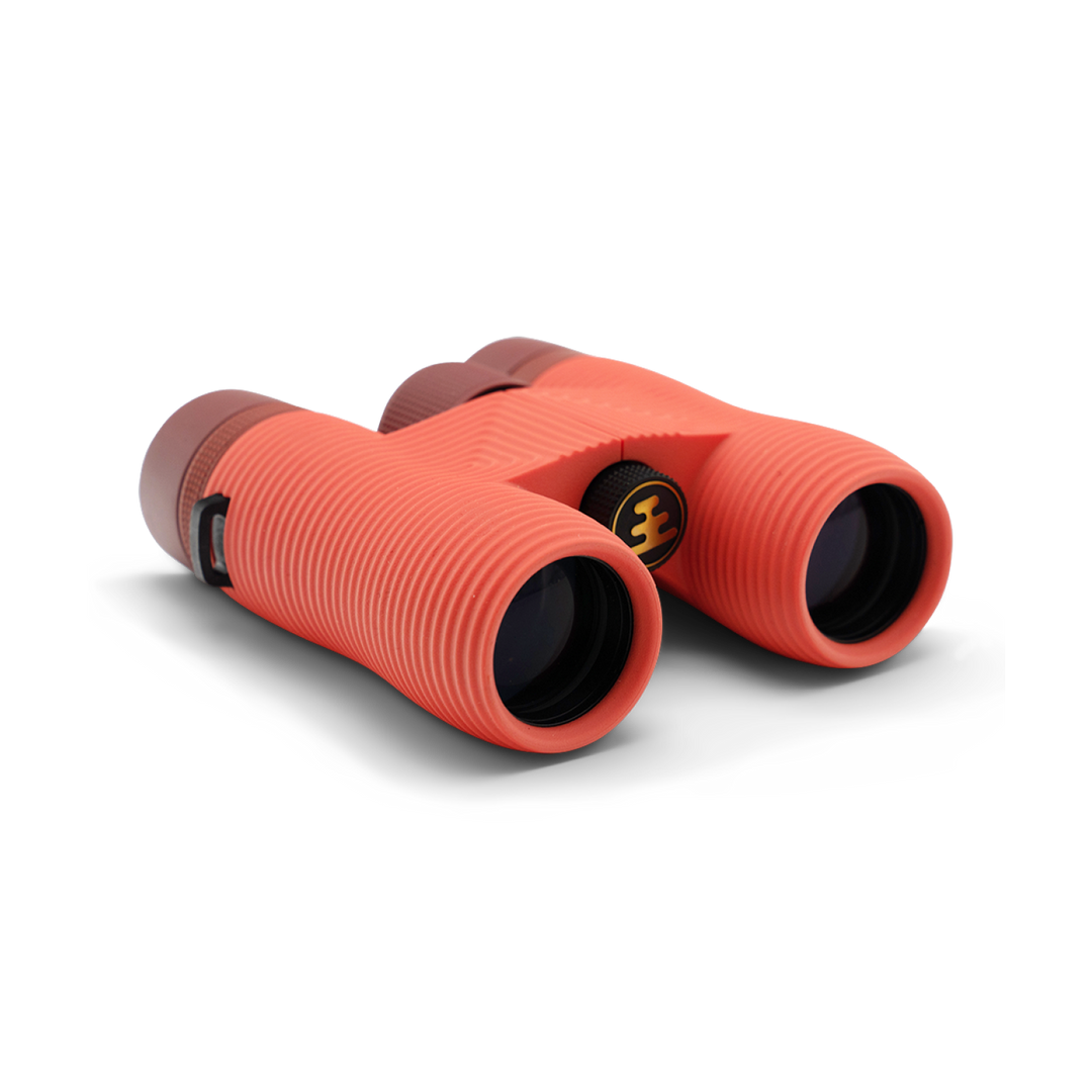 Compact orange binoculars with Nocs Provisions logo on a white background