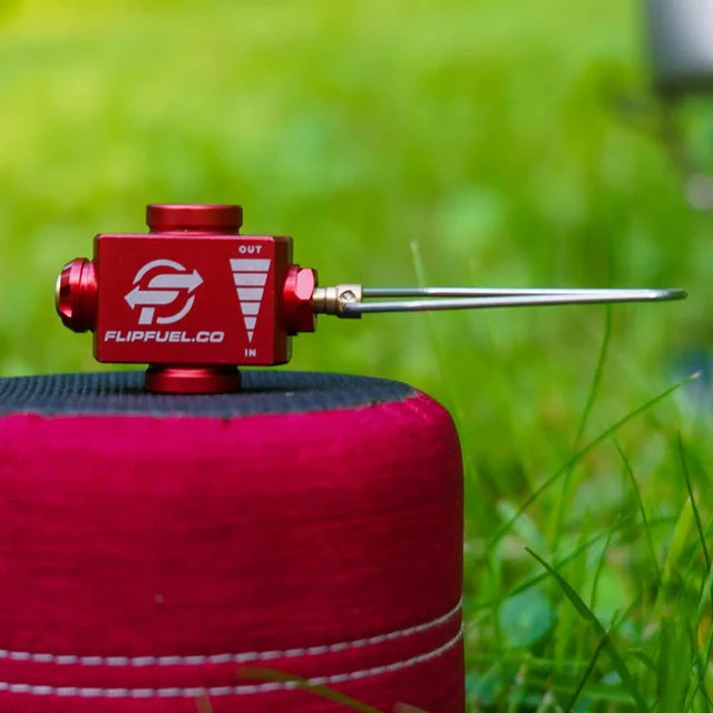 Red fuel valve on a red fuel canister with grass in the background