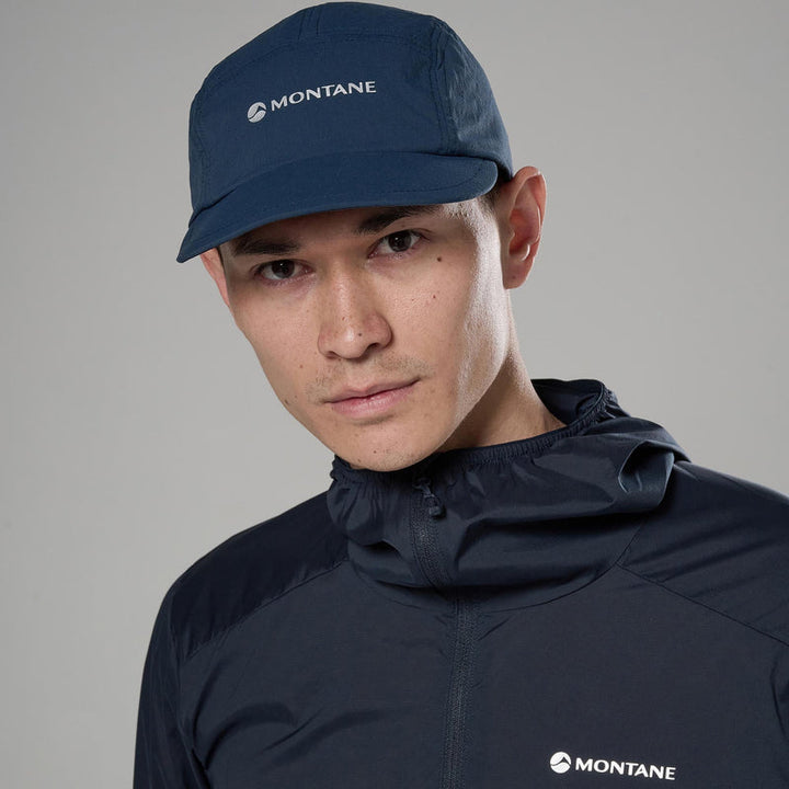 Person wearing a navy Montane cap and jacket on a gray background