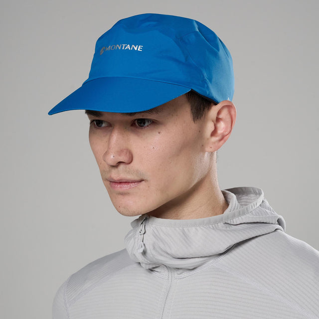 Person wearing a blue Montane cap against a grey background
