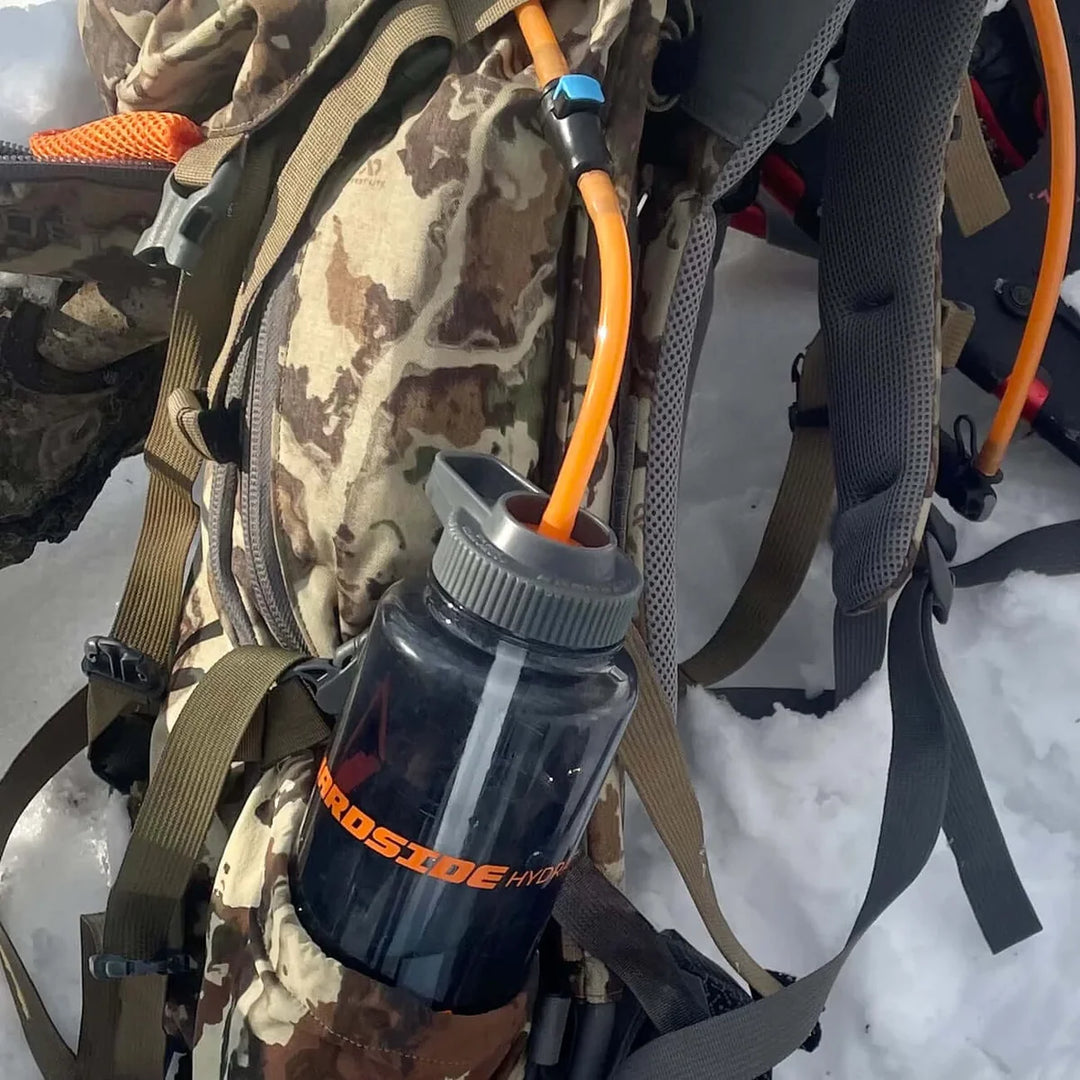 Hydration system attached to a backpack with an orange tube on a snowy background