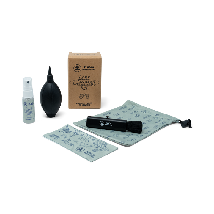 Nocs lens cleaning kit with spray bottle, blower, brush, and cloth on a white background