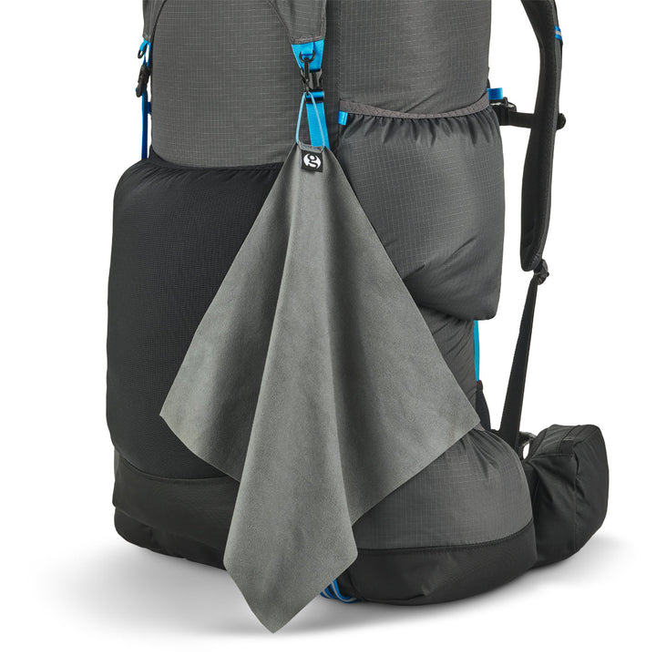 Grey backpack with a gray towel draped over it on a white background