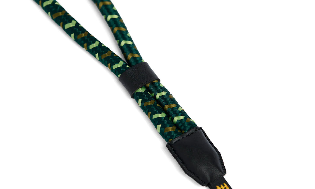 Green braided camera strap with black buckle on a white background