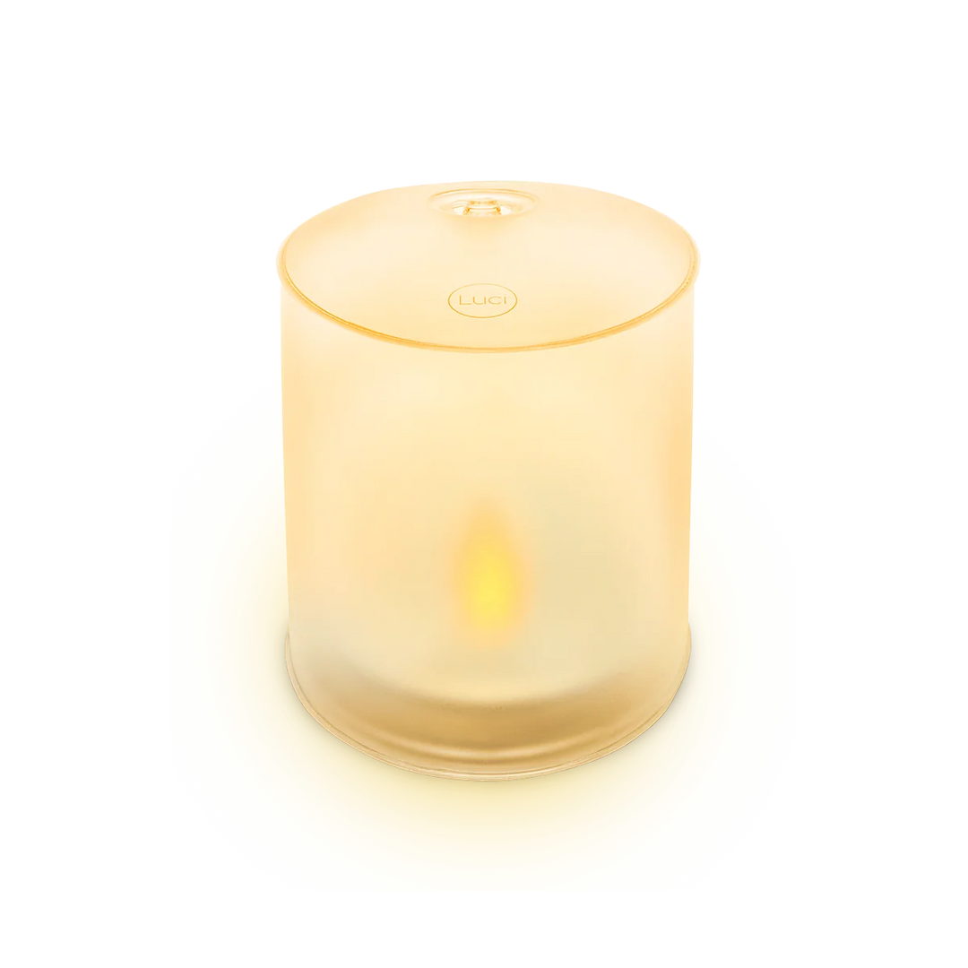 A frosted glass cylinder candle holder with a warm yellow glow from within, featuring a circular &