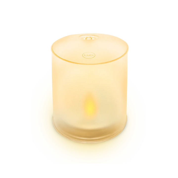A frosted glass cylinder candle holder with a warm yellow glow from within, featuring a circular &