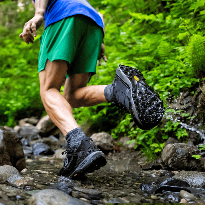 Person wearing Topo Terraventure 4 WP whil running along a shallow stream