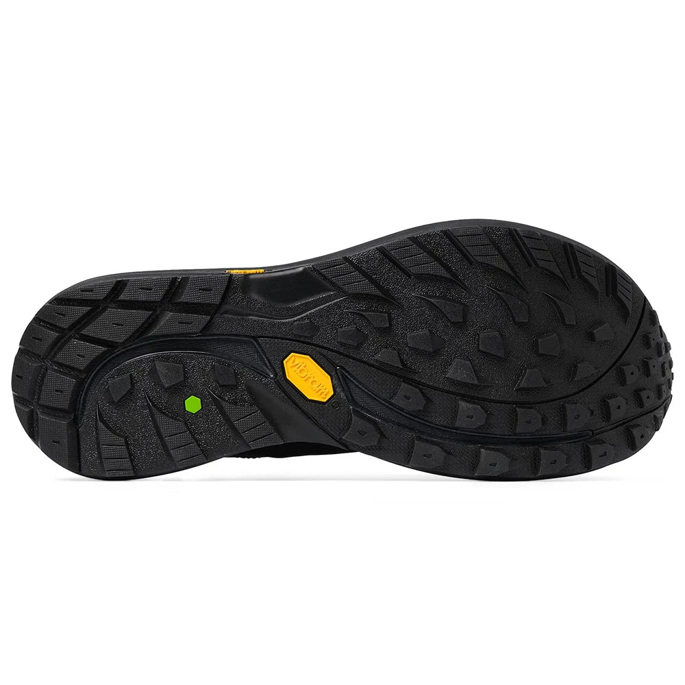 The black rubber outsole of a hiking shoe, showing deep tread patterns and a yellow Vibram logo on a white background.