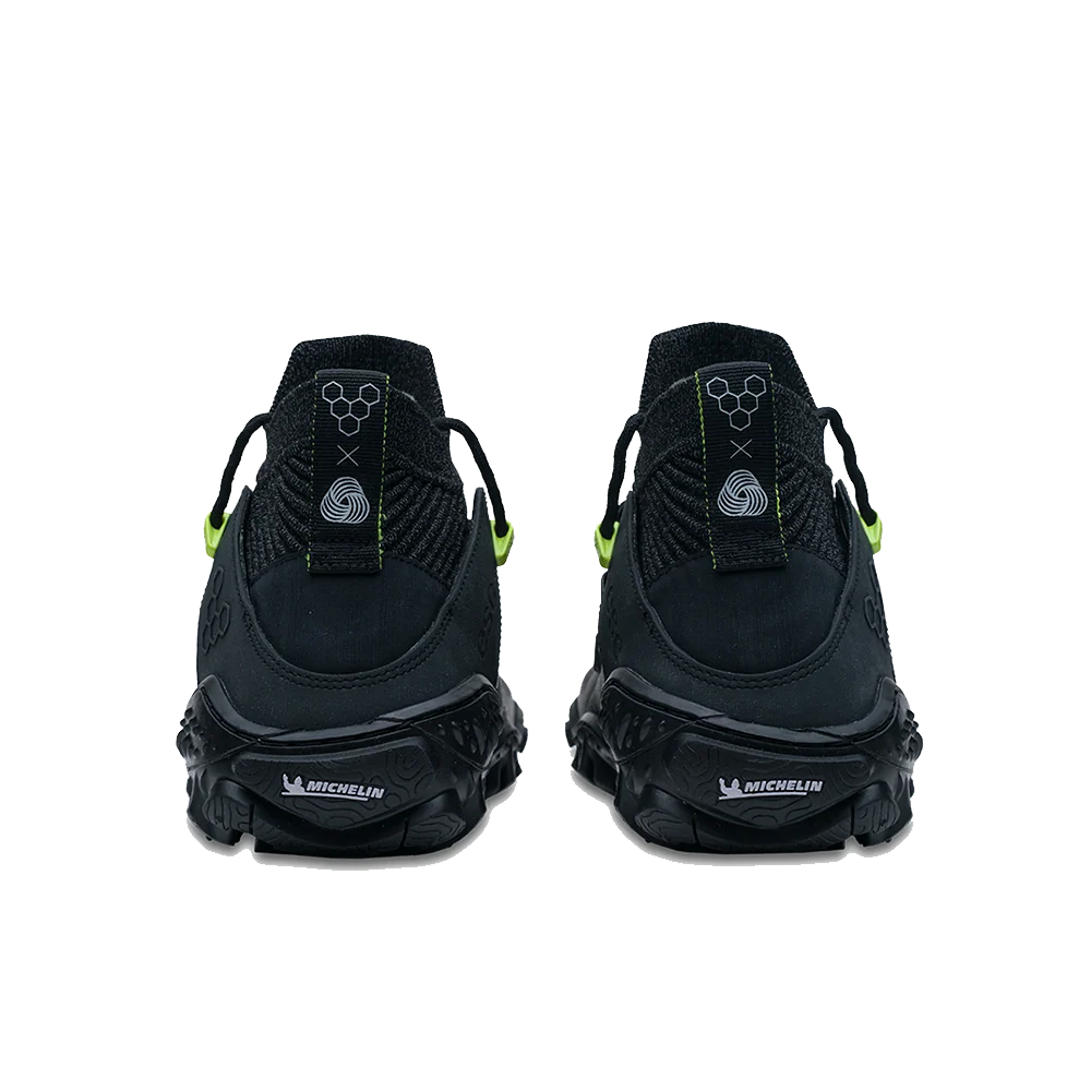 A pair of black athletic sneakers shown from the back, featuring textured black soles with white &
