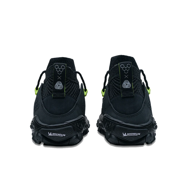 A pair of black athletic sneakers shown from the back, featuring textured black soles with white &