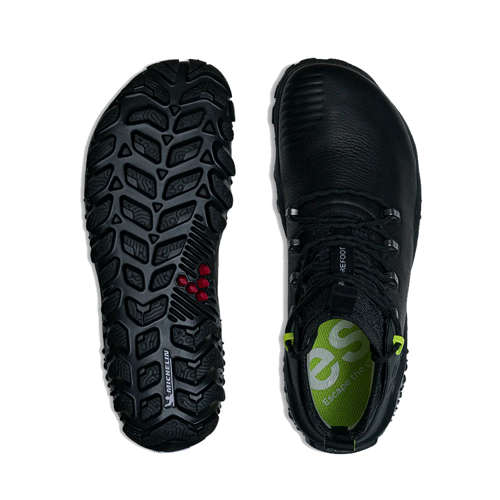 A pair of black outdoor boots shown from the top and bottom against a white background. The left boot displays the rugged black treaded Michelin Outland sole with small red accents, and the right boot shows the black leather upper with a green logo on the tongue.
