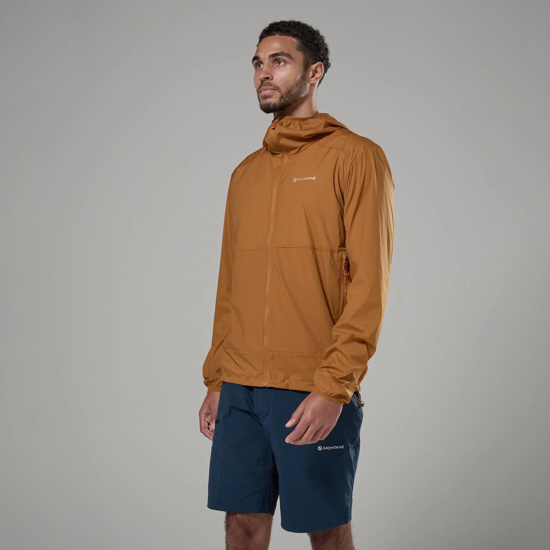Man wearing a brown jacket and navy shorts on a gray background