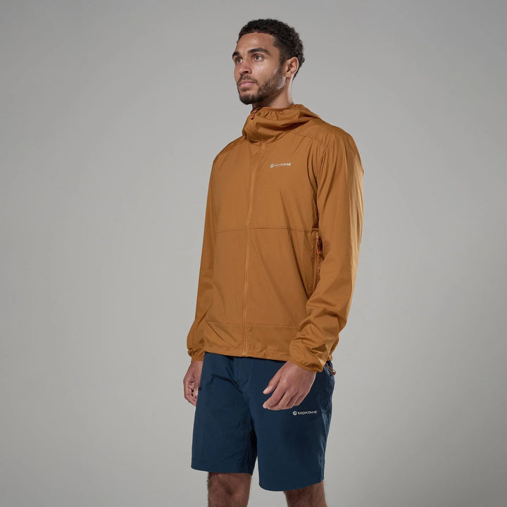 Man wearing a brown jacket and navy shorts on a gray background