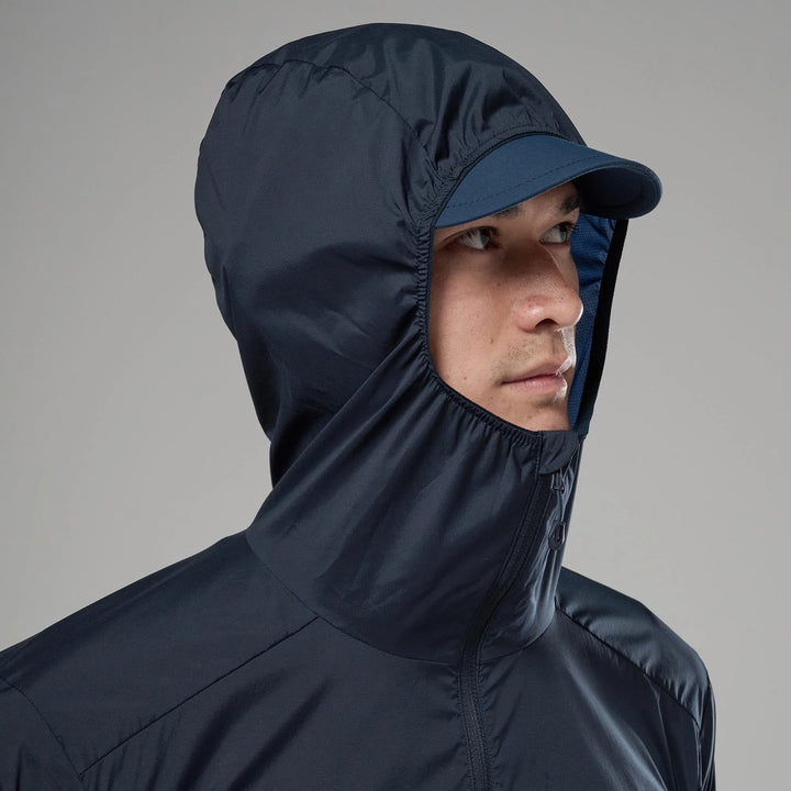 Person wearing a dark blue hooded jacket and cap against a gray background