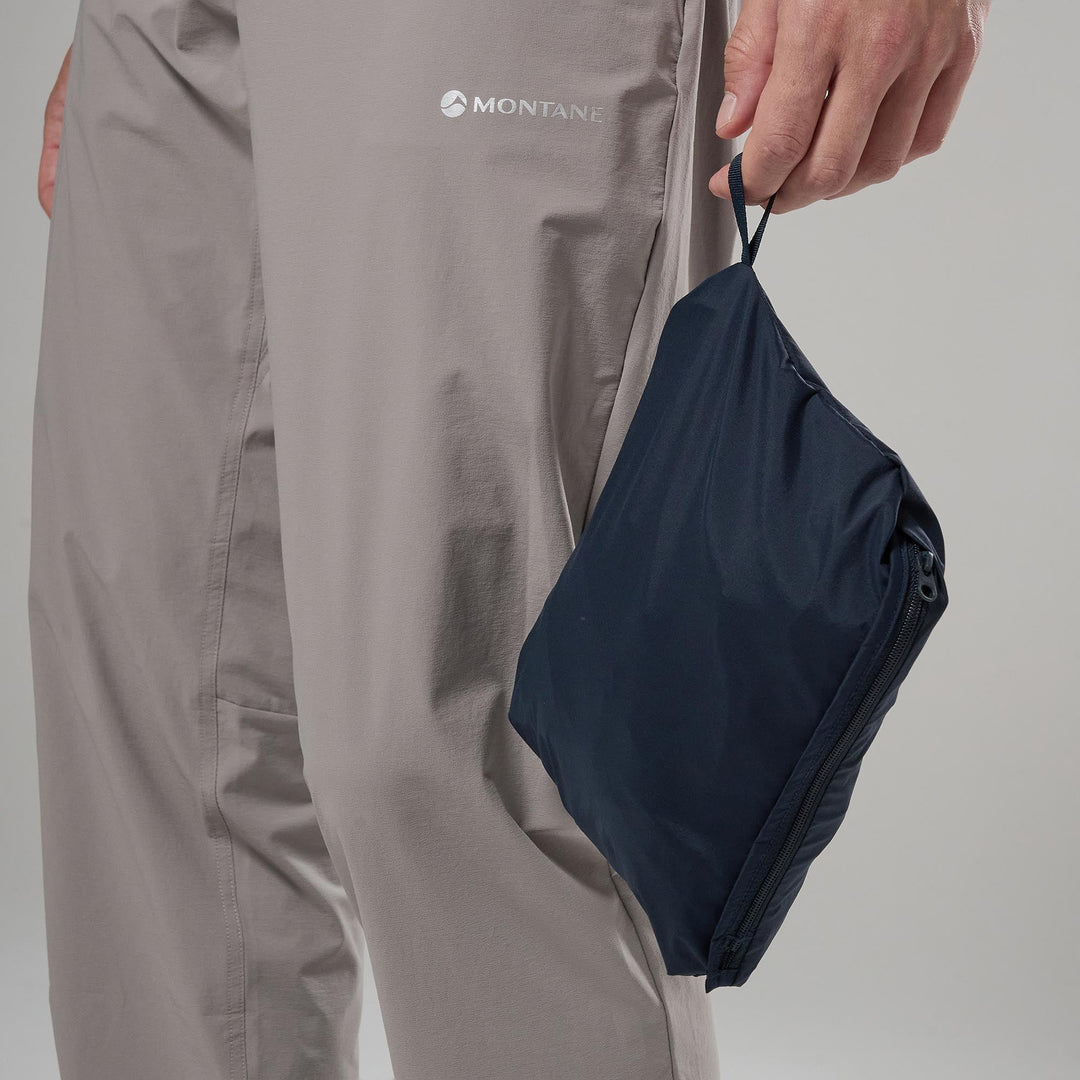 Person holding a navy blue pack with Montane logo on a gray background