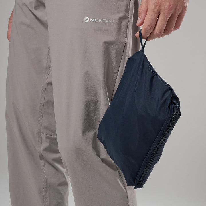 Person holding a navy blue pack with Montane logo on a gray background