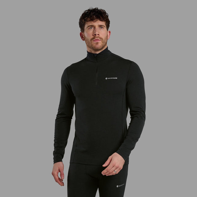 Man wearing a black long-sleeve athletic shirt with a logo on a grey background
