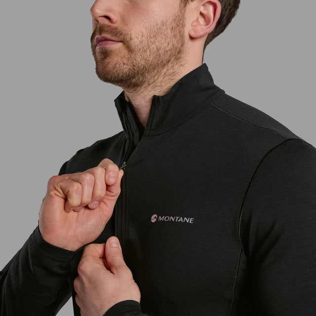 Person wearing a black Montane quarter zip shirt on a grey background