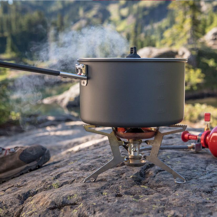 Camping stove with pot on a rock in a natural setting