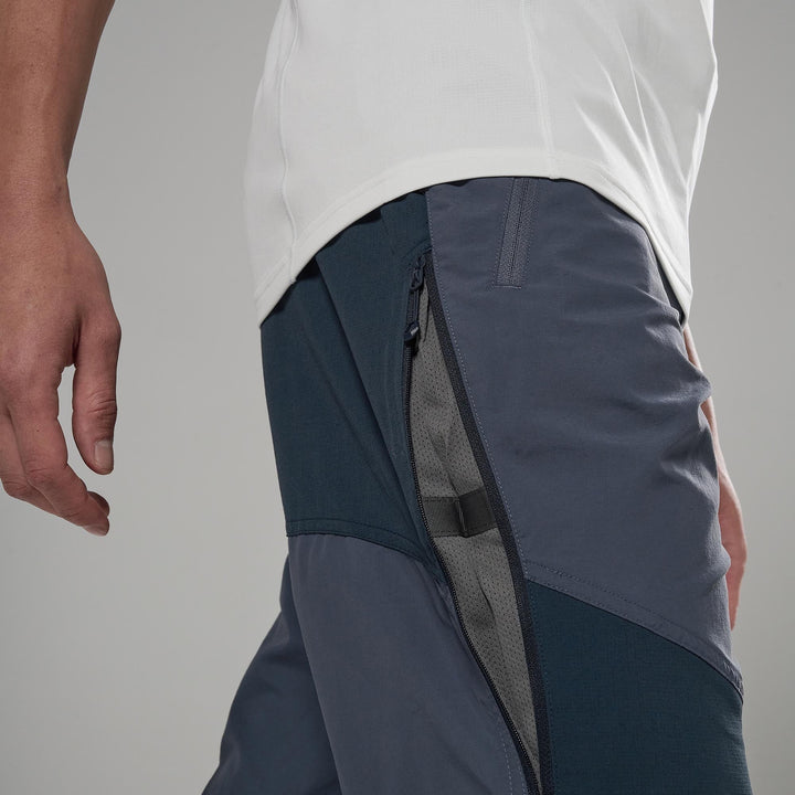 Person wearing dark gray athletic shorts with a white shirt on a gray background