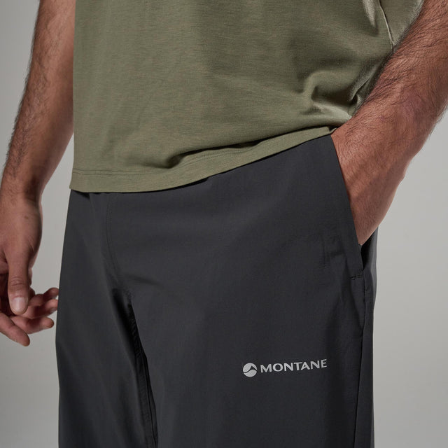 Person wearing a green shirt and black Montane pants on a grey background