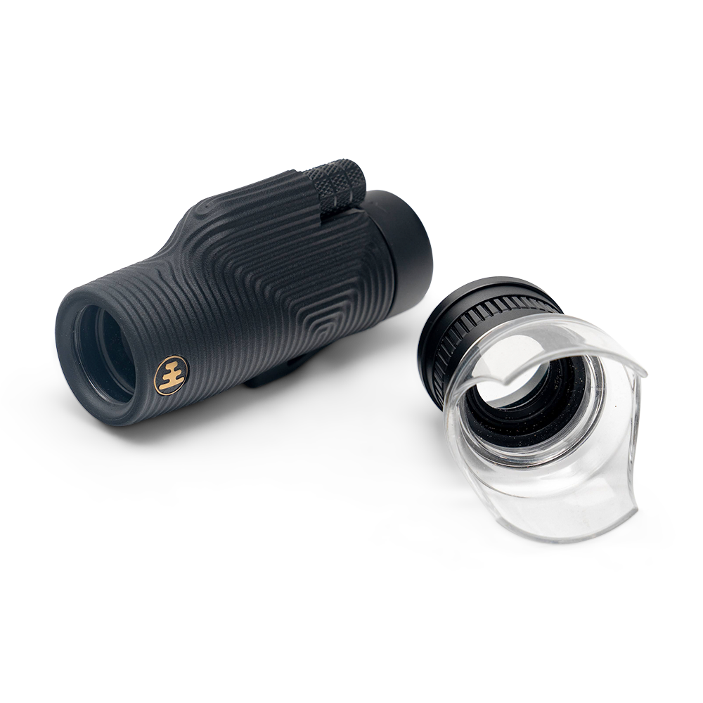 Black monocular telescope with lens cover on a white background