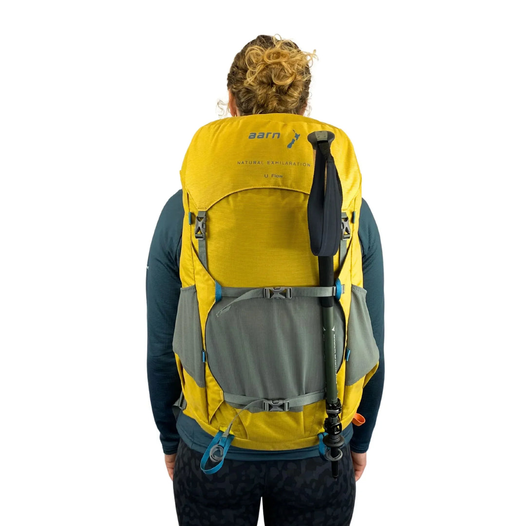 Person wearing a yellow and gray Aarn backpack on a white background