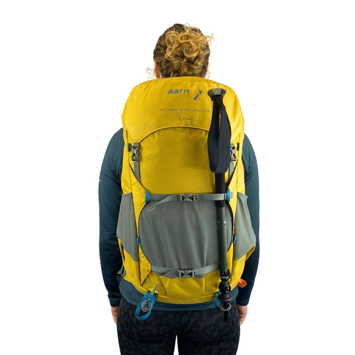 Person wearing a yellow and gray Aarn backpack on a white background