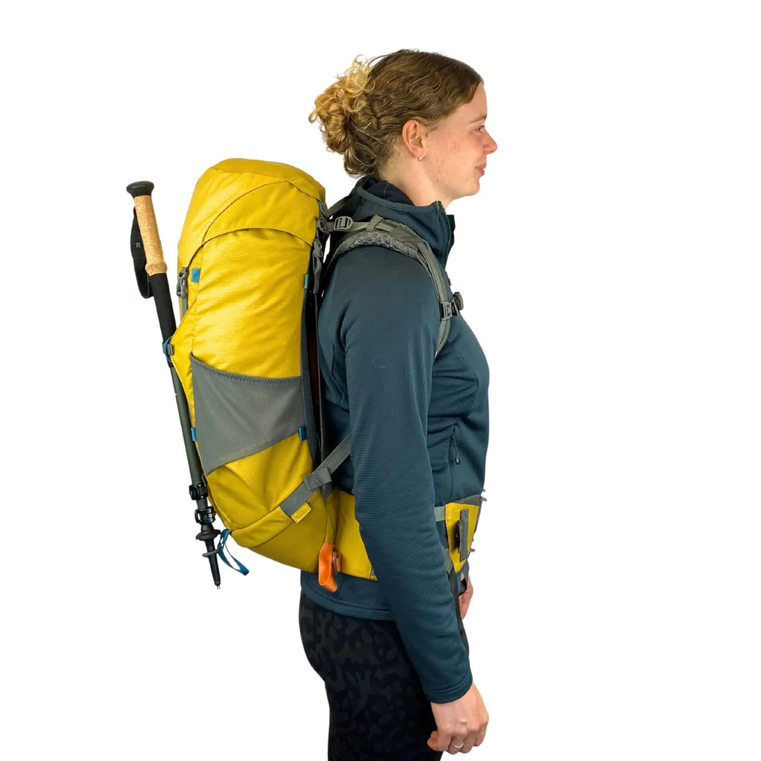 Person wearing a yellow and gray Aarn backpack on a white background