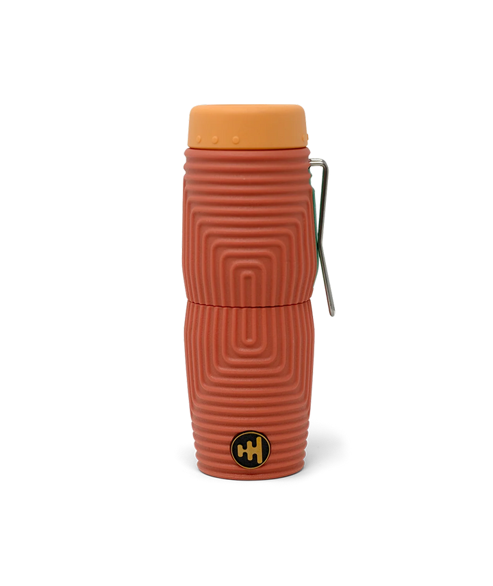 A terracotta coloured textured monocular with a light orange end cap and a silver metal clip over a green Nocs brand logo, shown on a white background.