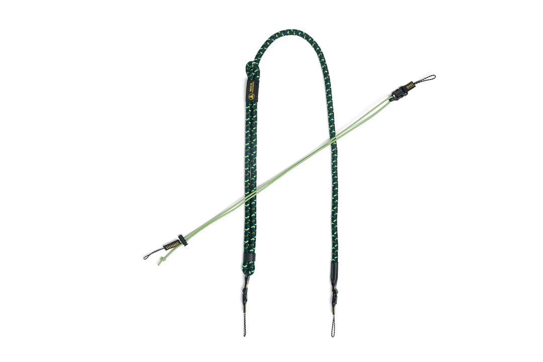 A green and black braided rope camera strap with metal clips and a small gold tag, displayed on a solid white background.