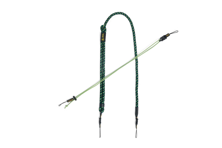 A green and black braided rope camera strap with metal clips and a small gold tag, displayed on a solid white background.