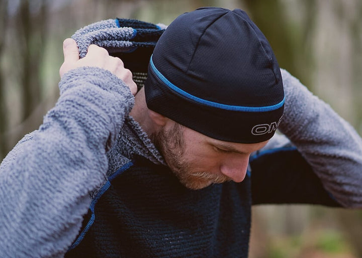 Person putting on the on of a black and grey hoodie, outdoors.