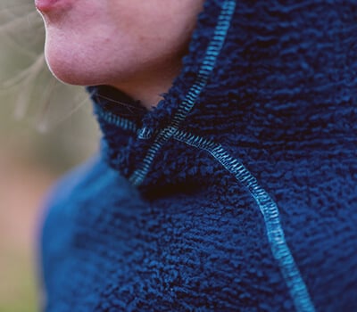 Close-up of a person wearing a blue fleece jacket with a blurred background