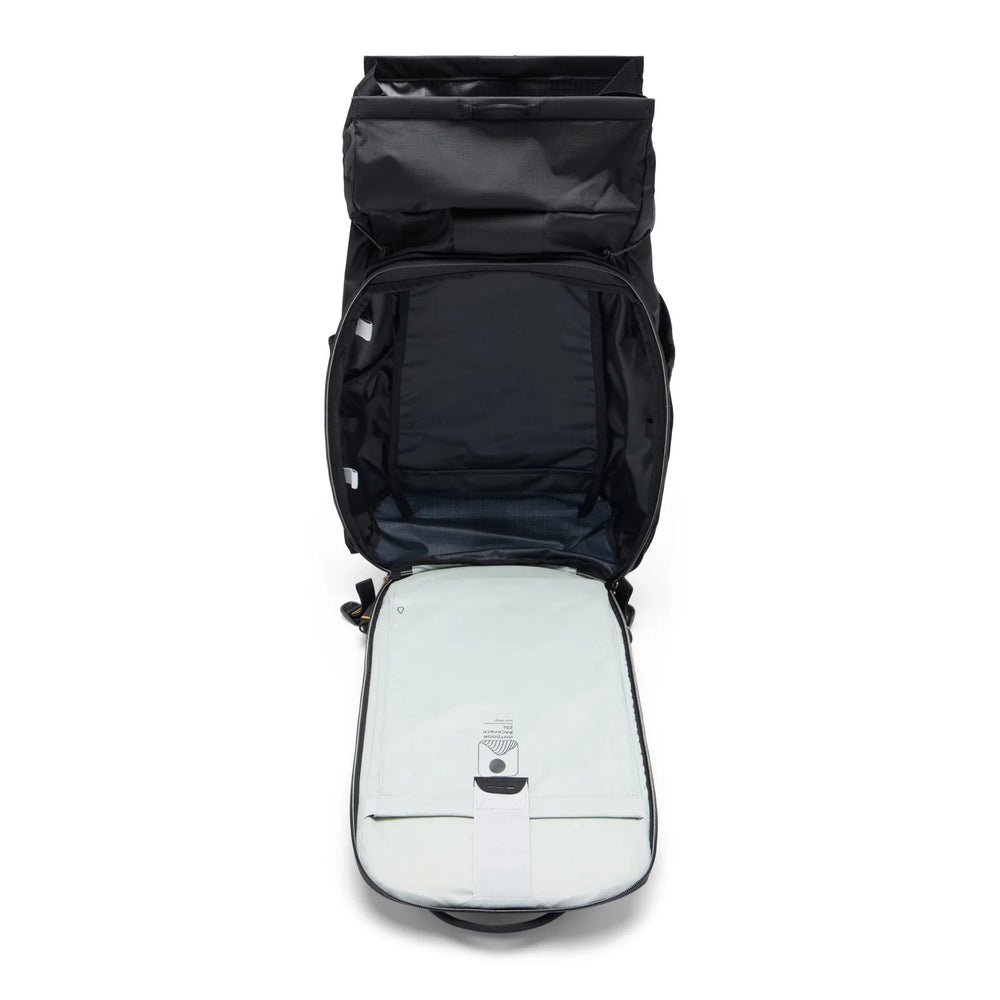 An open black backpack shown from above, revealing a light gray padded compartment inside with a small attached device on the front.