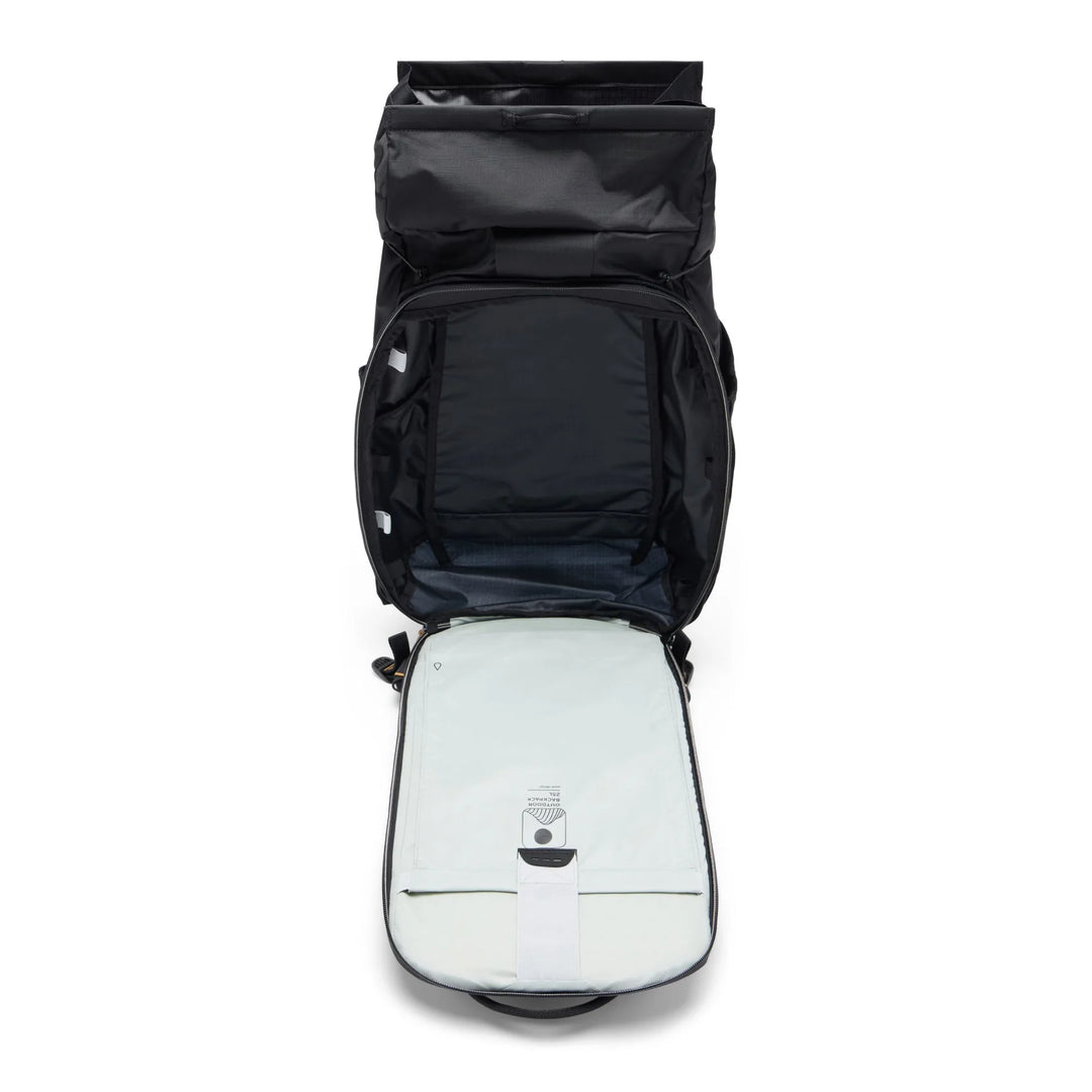 An open black backpack shown from above, revealing a light gray padded compartment inside with a small attached device on the front.