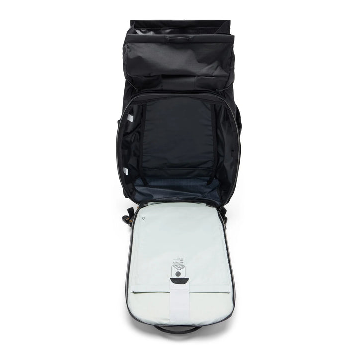 An open black backpack shown from above, revealing a light gray padded compartment inside with a small attached device on the front.