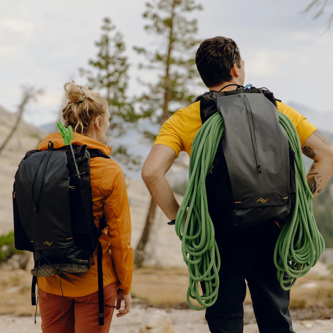 Two people hiking with climbing gear in a mountainous area