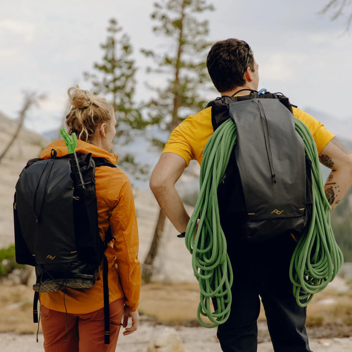 Two people hiking with climbing gear in a mountainous area