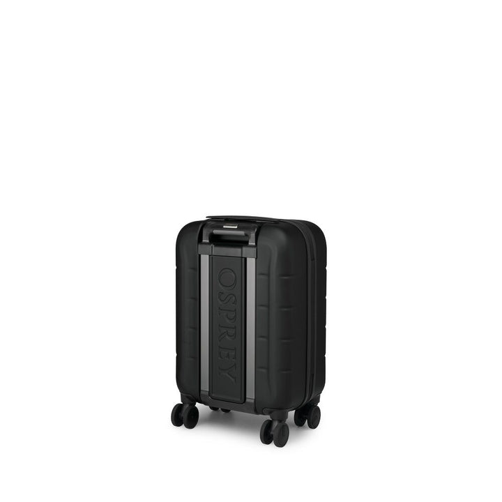 A black hard-shell suitcase with a textured wavy pattern, featuring an extended silver telescopic handle and four wheels, shown on a plain white background.