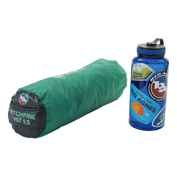 Green tent in bag next too blue water bottle.