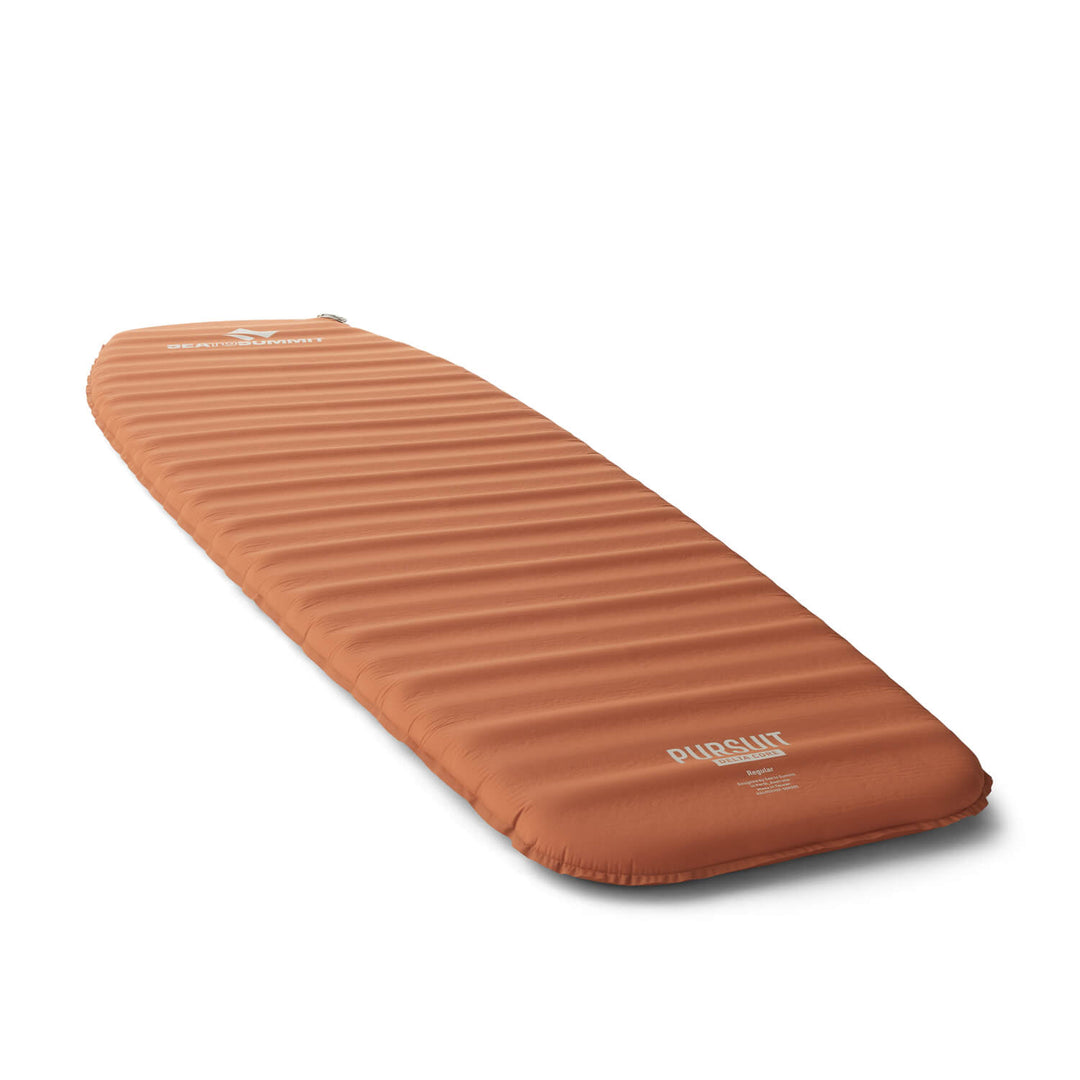 Orange mummy shaped sleeping mat on a white surface viewed at an angle