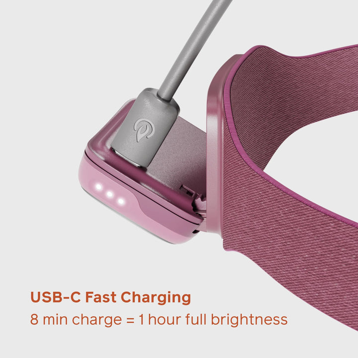 Pink electronic device with USB-C charging cable on a white background