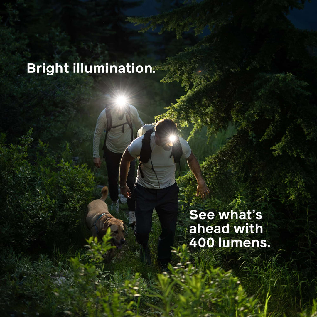 Two people and a dog hiking in the dark with headlamps, text highlighting 400 lumen brightness.
